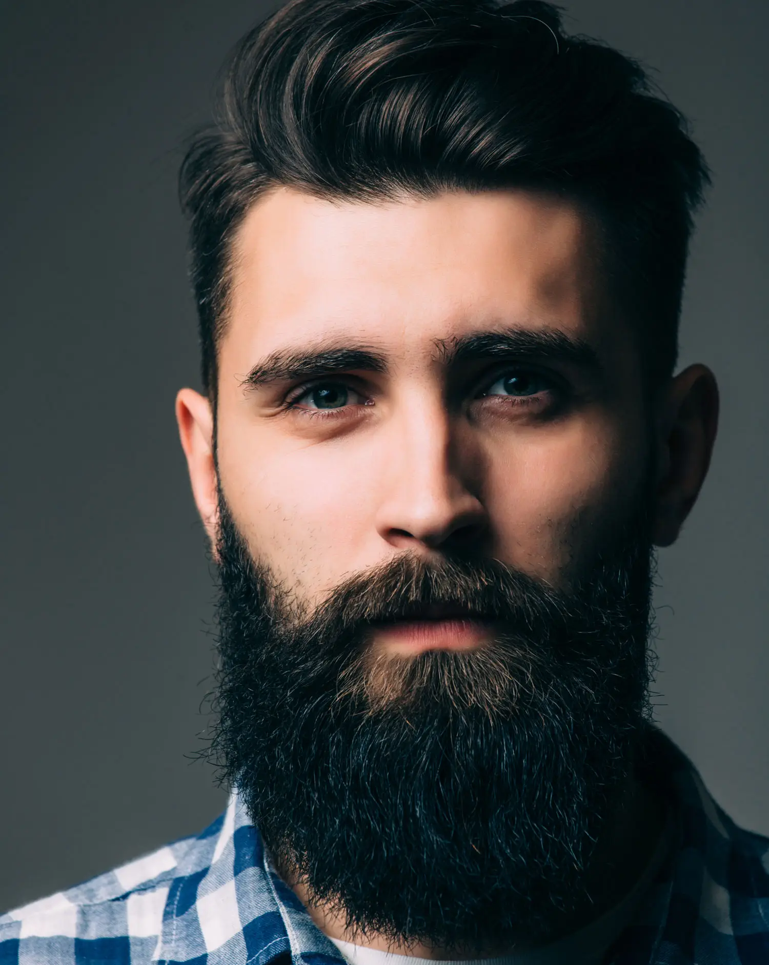 retrato masculinidad retrato joven guapo barba mientras pie contra pared gris